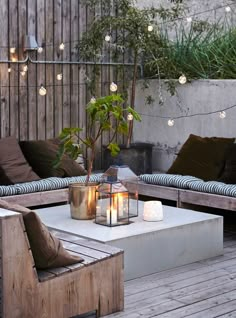 an outdoor living area with couches, tables and lights