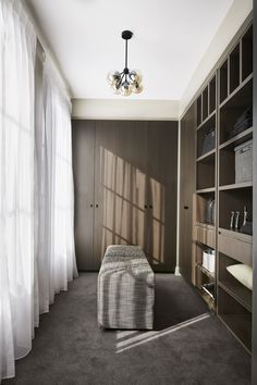 a living room with a couch, bookcases and window curtains on the windowsill