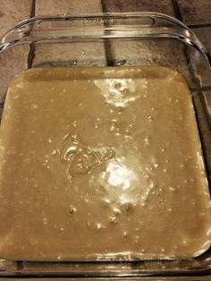 a glass dish filled with batter on top of a tile floor