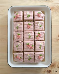 a white plate topped with lots of pink frosted cake next to a wooden table