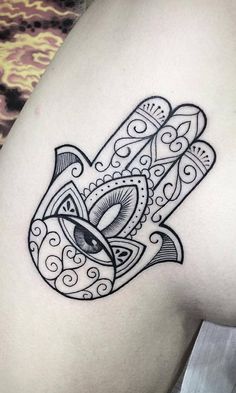 a black and white hamsa tattoo on the back of a woman's shoulder