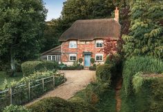 an old brick house surrounded by hedges and trees