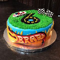 the birthday cake is decorated with cars and grass