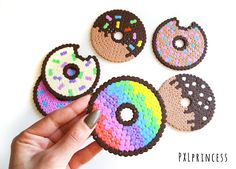 a hand is holding four donuts made out of crochet