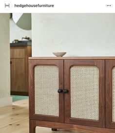 a wooden cabinet with wicker doors on the front and side, sitting in a living room