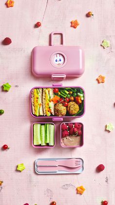 a pink lunch box filled with food on top of a table