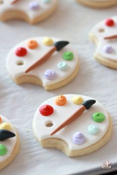 decorated sugar cookies with paintbrushes and buttons on the top one cookie has white icing