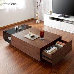 a modern living room with wood flooring and large tv on top of the coffee table