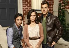 two men and a woman sitting on steps in front of a house