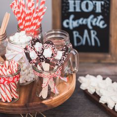 some cookies and marshmallows are in glass jars on a table with candy canes