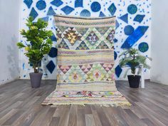 a large multicolored rug sitting on top of a wooden floor next to a potted plant