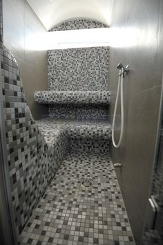 a bathroom with tiled walls and flooring next to a shower head mounted on the wall