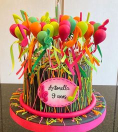 a cake decorated with balloons and streamers on top of a black tablecloth covered surface