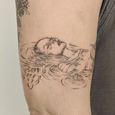 a man with a tattoo on his arm is in the water and has a woman's face drawn on it