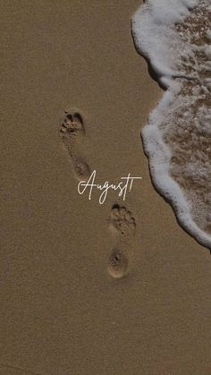 two footprints in the sand next to an ocean shore with words august written on it