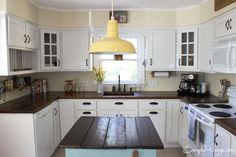 a kitchen with white cabinets and wood counter tops, an island bench in the middle