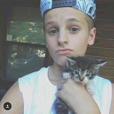 a young boy holding a small kitten in his arms and wearing a crown on top of his head