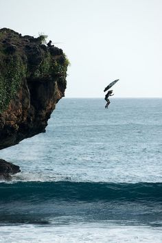 a person jumping off the cliff into the ocean