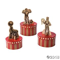 three wooden toy figurines sitting on top of a red and white striped box