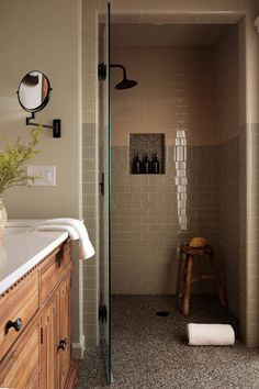 a bathroom with a walk in shower sitting next to a sink and counter top under a mirror