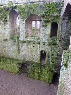 an old building with moss growing on it's walls and some windows in the wall