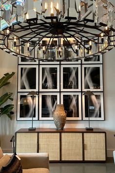 a chandelier hanging from the ceiling in a living room with pictures on the wall