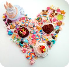 a heart shaped cake surrounded by various candies and other sweets on a white surface