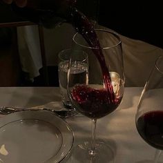 a person pouring wine into two glasses on a table