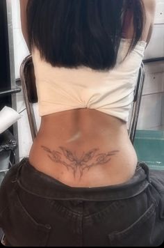 a woman sitting in a chair with her back turned to the camera and tattoos on her stomach