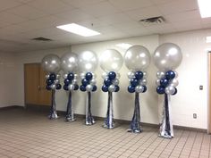 balloons are lined up in the middle of a room with silver and blue decorations on them