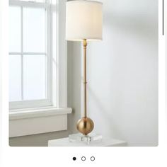 a lamp that is on top of a table next to a window with the light on