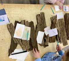 a young child is drawing on wood with colored pencils