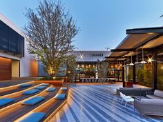 an outdoor lounge area is lit up with lights and seating for people to sit on