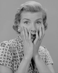 a black and white photo of a woman covering her mouth