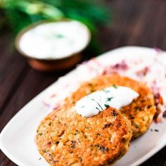 two crab cakes on a white plate with sour cream and parsley in the background