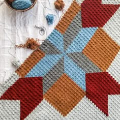 a crocheted blanket is next to a bowl with yarn