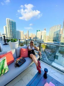 a woman sitting on top of a couch in front of a cityscape with high rise buildings