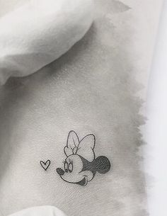 a small tattoo on the back of a woman's neck, with a cartoon mouse flying