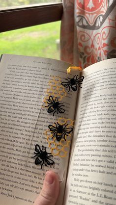 a person holding an open book with black and yellow spider decorations on it