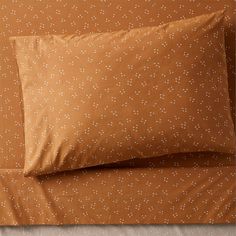 two pillows on top of each other next to an orange pillow case with white dots