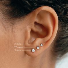 a woman's ear is shown with three small diamond studs