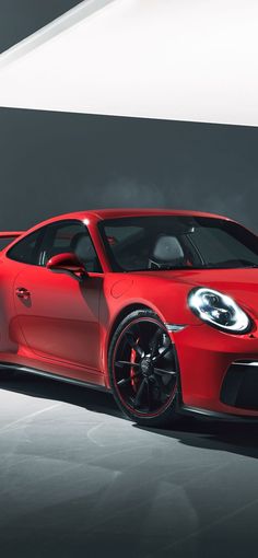 a red sports car is parked in a dark room with its hood up and lights on