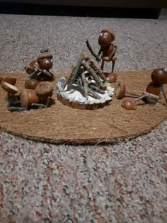 there are many small figurines sitting on the floor next to some rocks and twigs