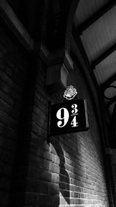 a black and white photo of a sign hanging from the side of a brick building