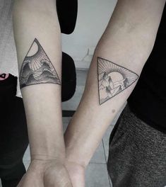 two people holding hands with tattoos on their arms