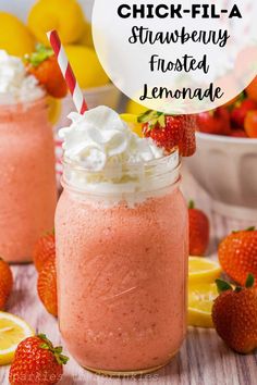 two mason jars filled with strawberry lemonade and whipped cream topped with fresh strawberries