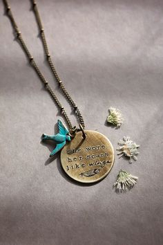 a necklace with a bird and quote on it