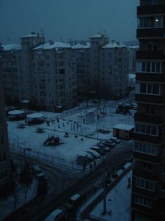 an empty parking lot in front of apartment buildings on a snowy day with no one around