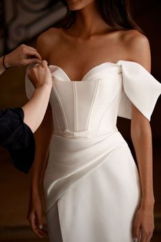 a woman in a white dress getting ready to go on her wedding day with the help of a man