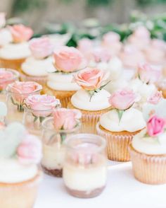 cupcakes with pink flowers on them sitting on a table next to each other